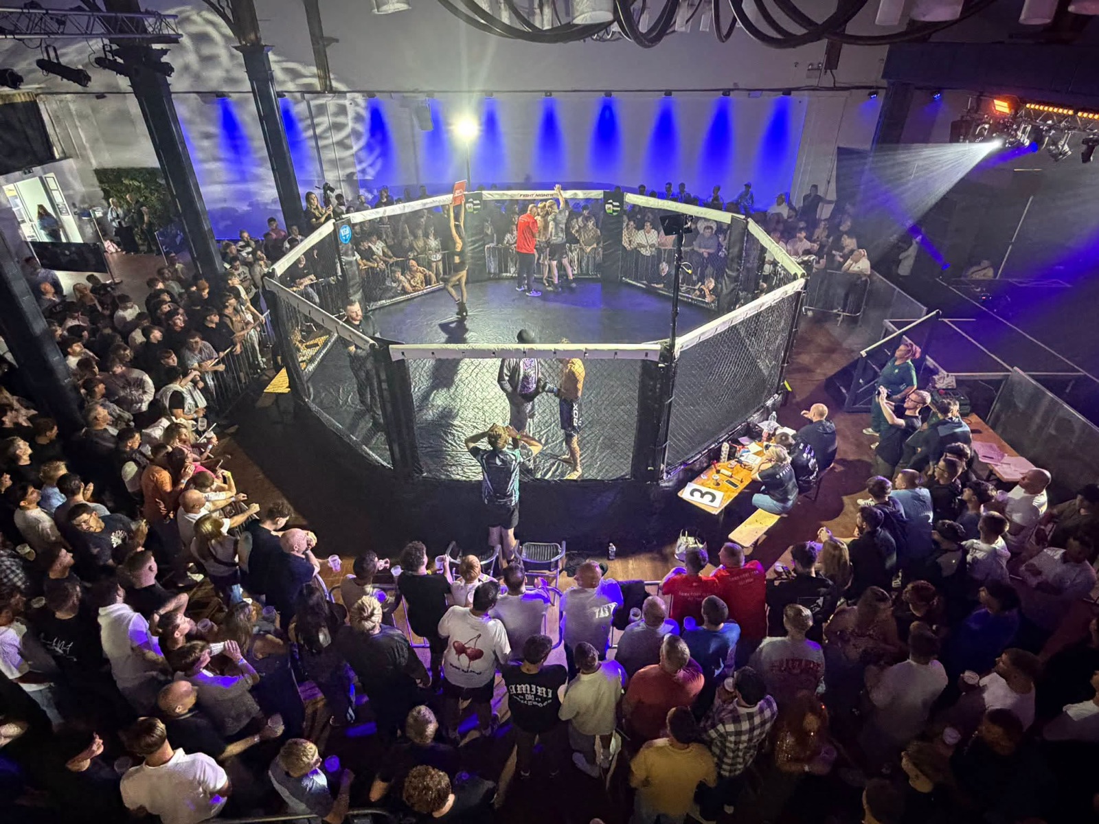 A crowded amateur MMA event viewed from above the cage